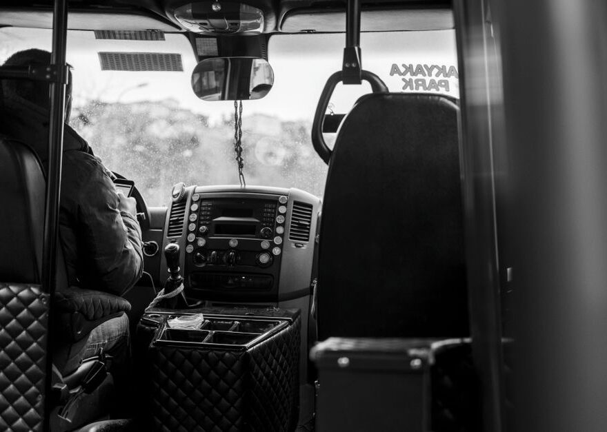 Een buschauffeur in Hellevoetsluis die passagiers verwelkomt aan de busdeur, met een mooie stadsachtergrond.